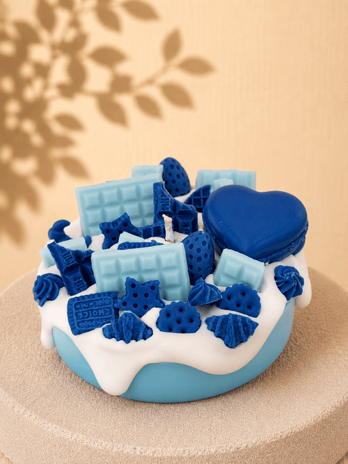 Blue Crush cake-style scented candle with light blue base, white frosting and light and dark blue sweet-inspired wax decorations
