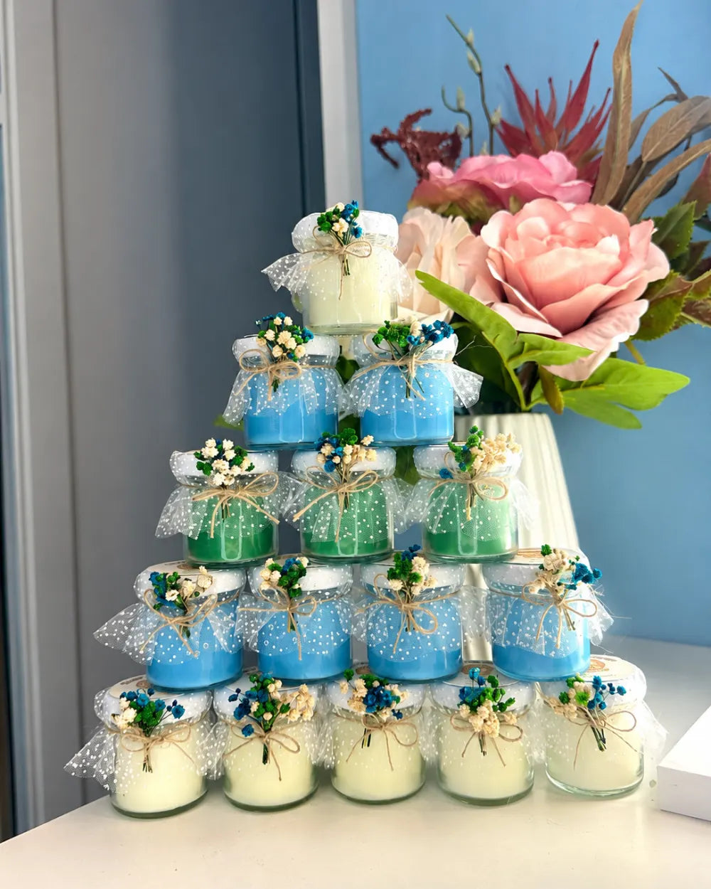 Blue, green and ivory personalised candle favours decorated with dried flowers, tulle and twine bows
