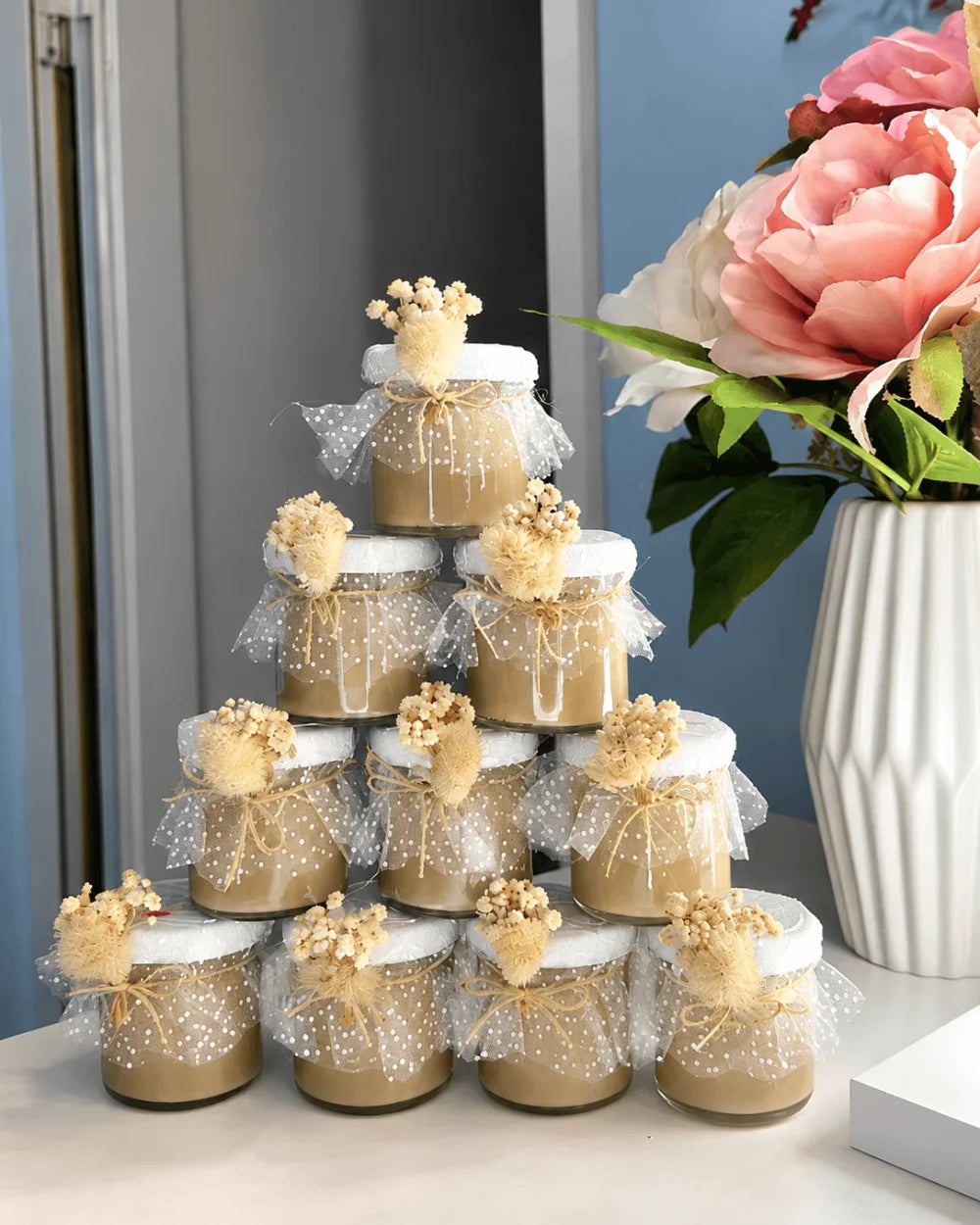 Neutral beige candle favours decorated with dried flowers, tulle and twine bows