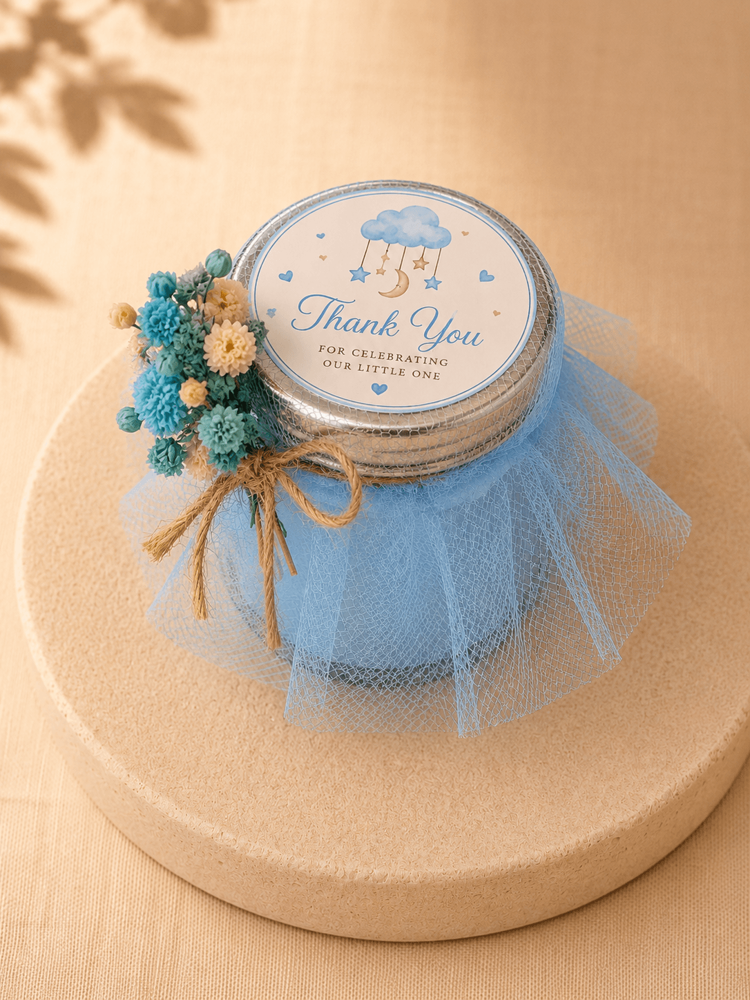 Blue baby shower candle favour wrapped in tulle with a thank you label and dried flower decoration.