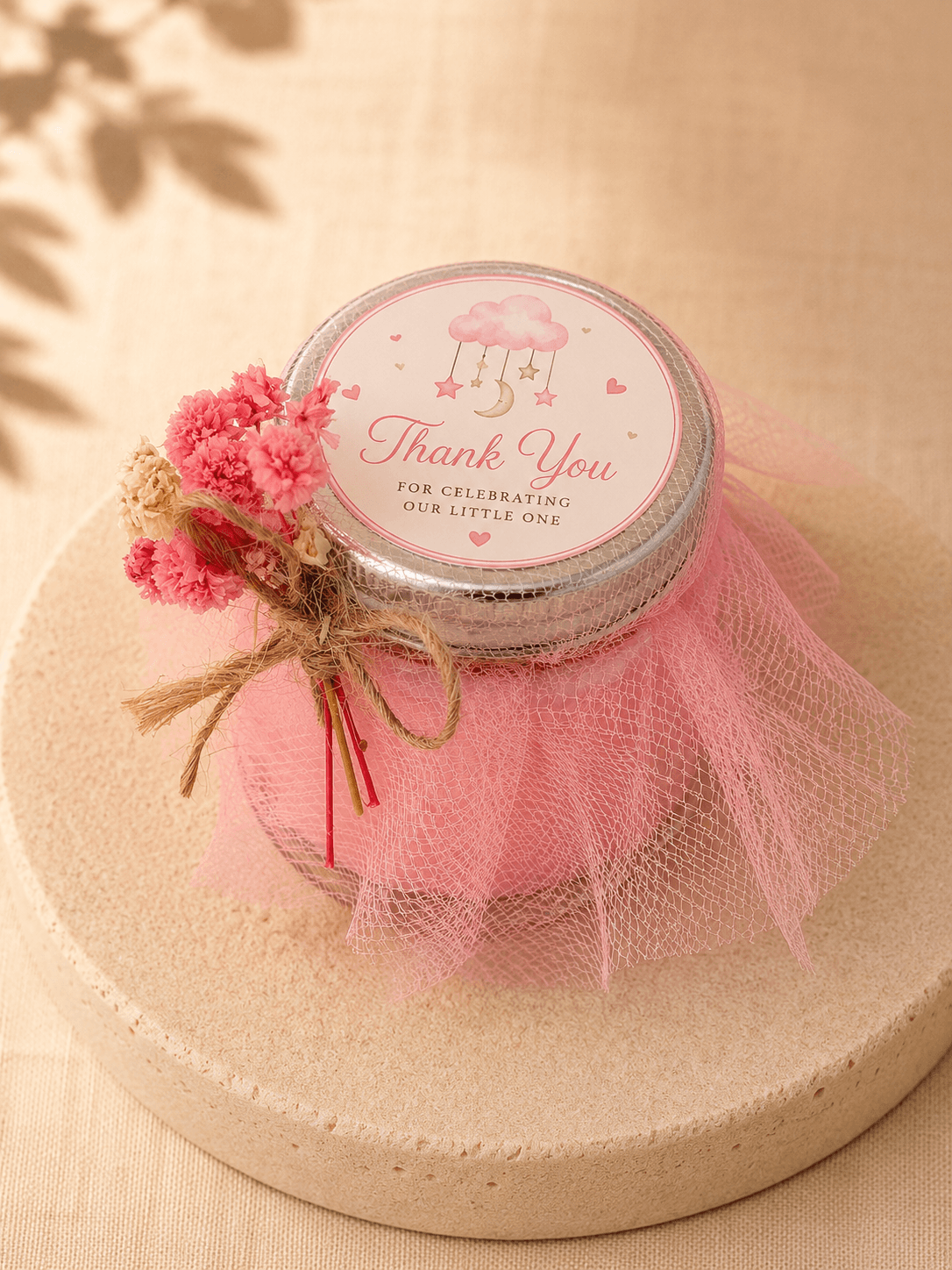 Pink baby shower candle favour wrapped in tulle with a thank you label and dried flower decoration.