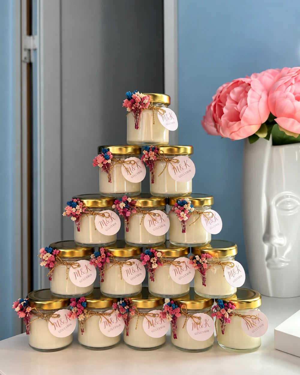 Personalised candle favours with floral details and gold lids arranged for a special event