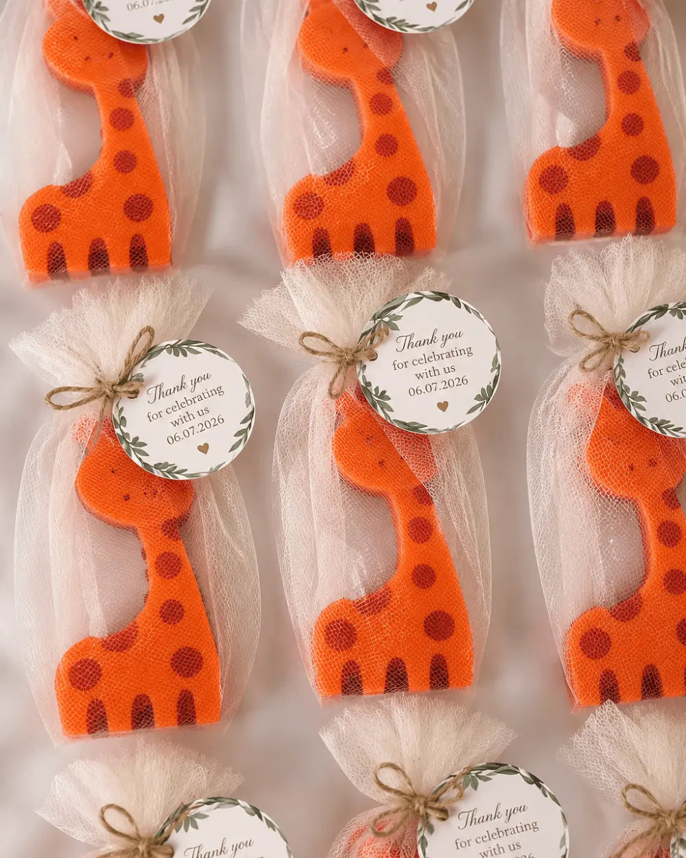 Giraffe-shaped candle favours in organza bags with personalised thank you tags