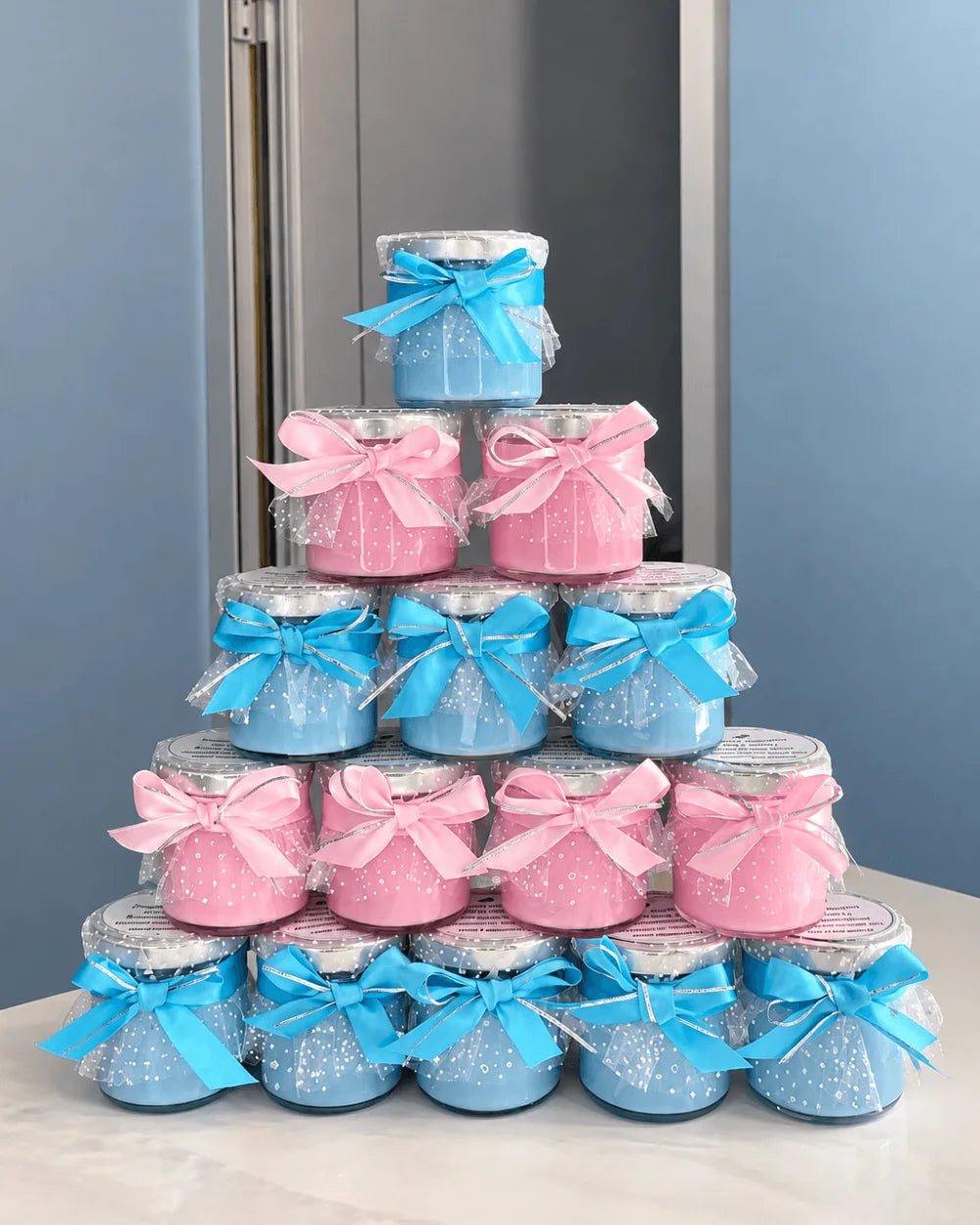 Pink and blue personalised candle favours decorated with matching bows and tulle