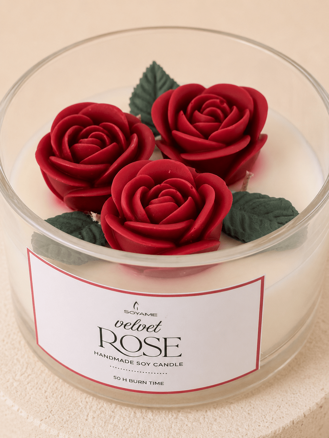 Close-up of the Velvet Rose scented soy candle with three red rose and leaf details
